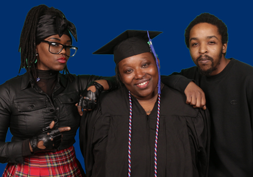 Jessica Whittaker, center, is dressed in graduation attire as the first graduate from the SCC Prison Education Program. She is celebrating with a smile on her face surrounded by friends, a female and male also wearing black. 