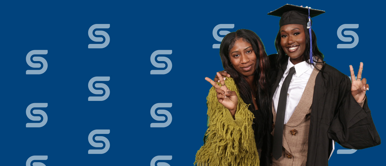 Two students pose for photos after the fall 2024 graduation ceremony. 