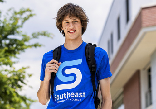 Ryder Claypool smiling on the Milford Campus in a short sleeve blue SCC shirt. 