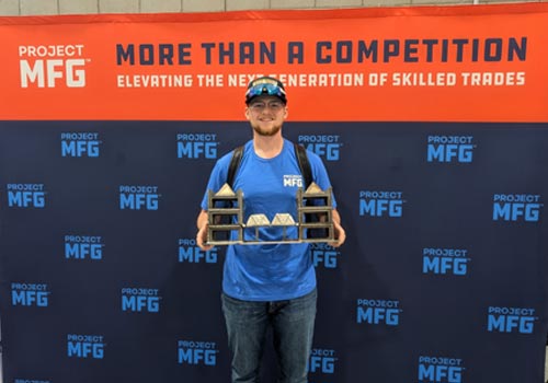 Nash Peterson stands holding a bridge he welded for the ProjectMFG National Final in San Diego